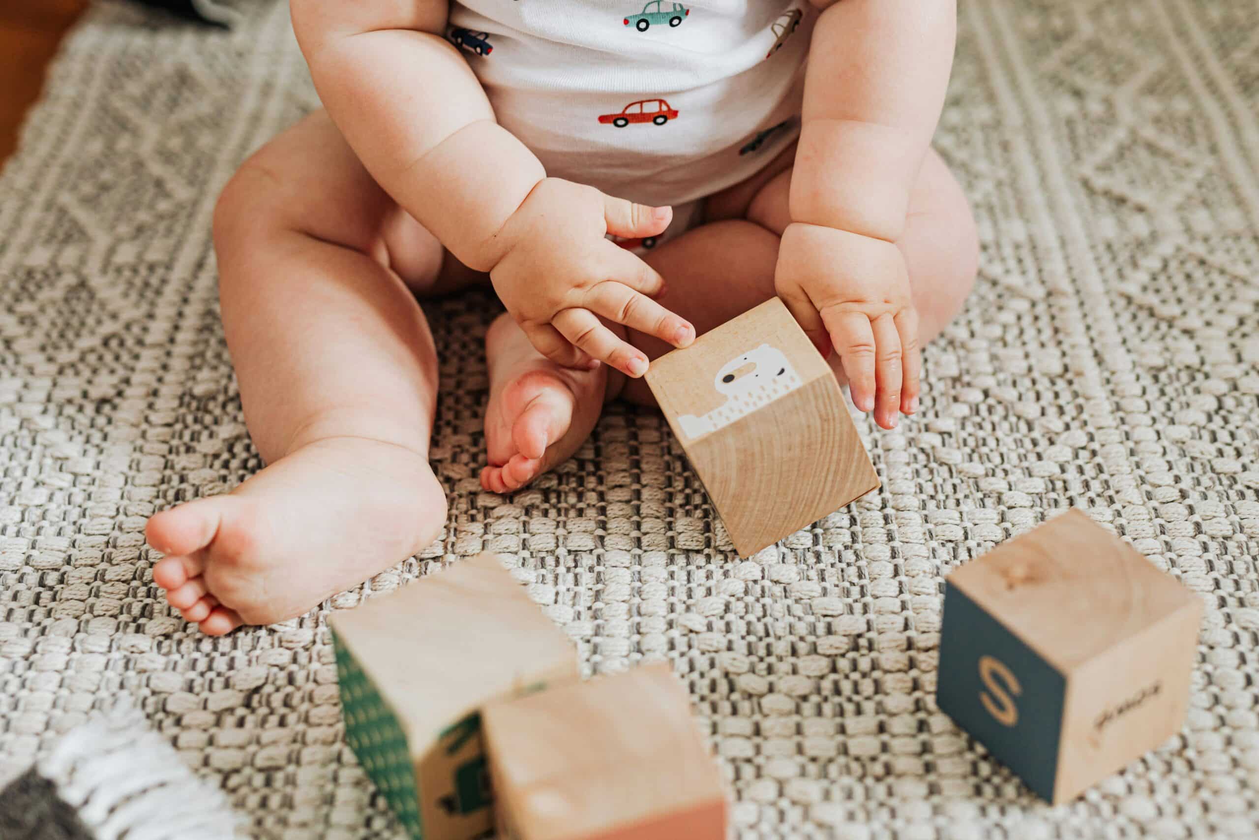 A baby plays with blocks on the floor.
